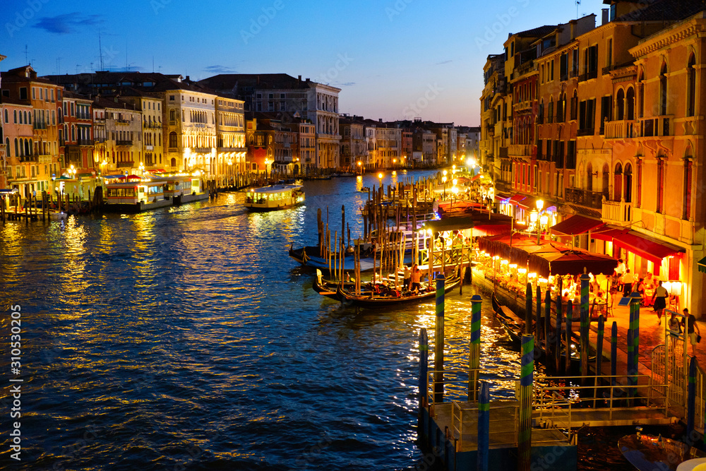 Grand Canal in Venice, Italy at night. View on gondolas and city lights from Rialto Bridge. Beautiful and romantic Italian city on water. 