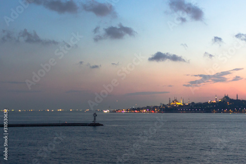 Sea port. Bosphorus Strait. View of Istanbul. Coast resort town. Ferry on the water. Ship at sea. Sunset sky. Sky gradient. Seascape in Istanbul. City on the horizon. Pink and blue shades. © Larysa