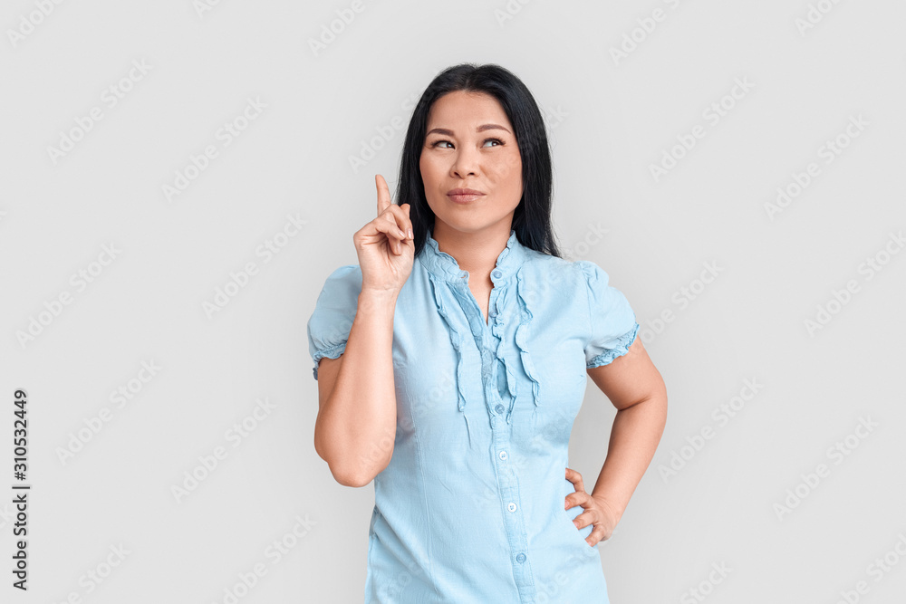 Freestyle. Asian woman standing isolated on white pointing up pensive finding solution Freestyle. Asian woman standing isolated on white pointing up pensive finding solution