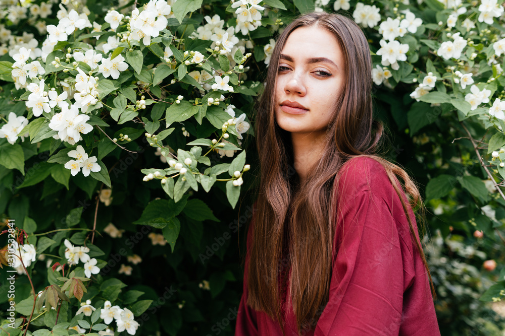 beautiful girl with long hair stands by a flowering jasmine bush beautiful girl with long hair stands by a flowering jasmine bush