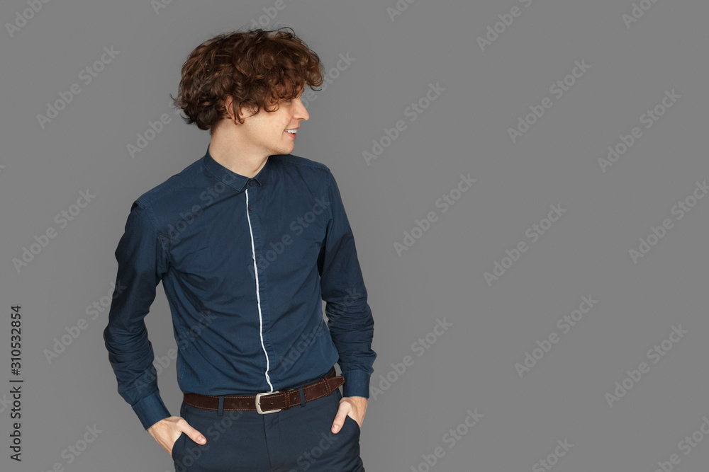 Fototapeta premium Space for Text or Product. Teenager boy standing isolated on grey looking at space aside laughing playful