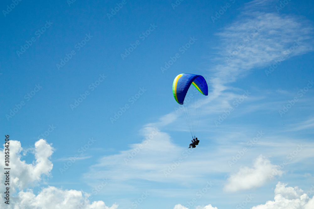 Naklejka premium Paraglider in the blue sky. The sportsman flying on a paraglider.