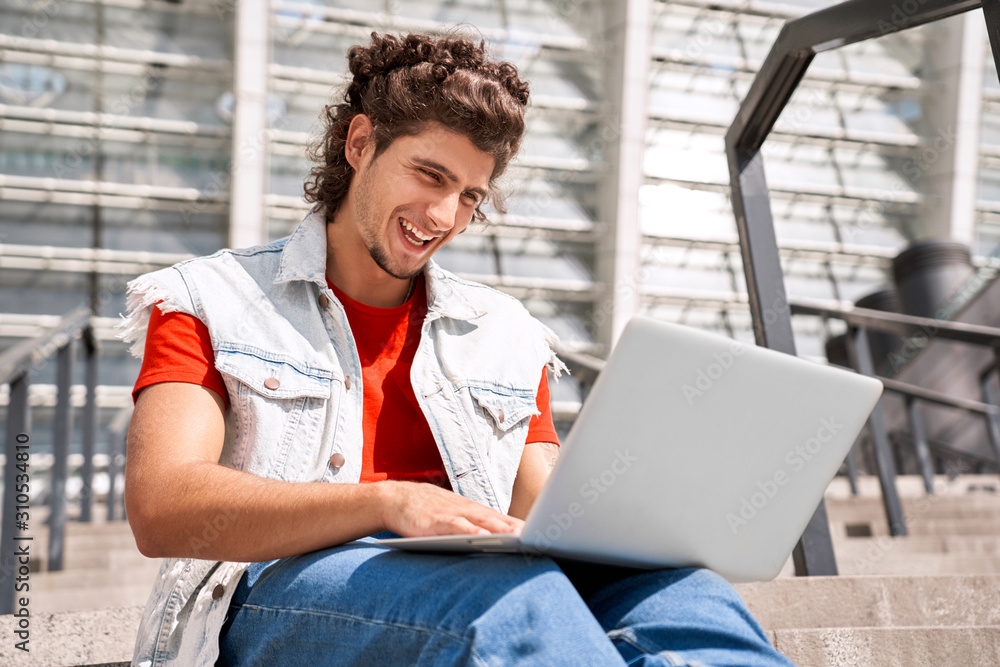 Young adult guy using laptop computer and smiling wide