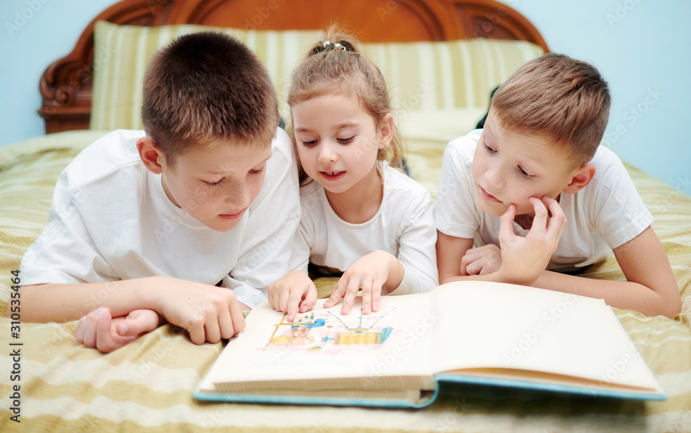 Three children are looking into a book only Three children are looking into a book only