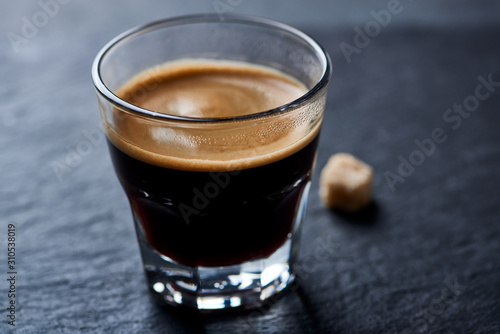 Coffee in glass cup on dark stone background. 