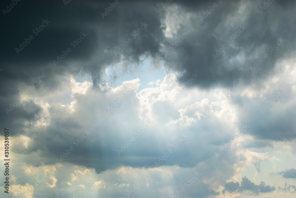 The sun's rays break through rare gaps among the dark thunderclouds hiding the sky The sun's rays break through rare gaps among the dark thunderclouds hiding the sky