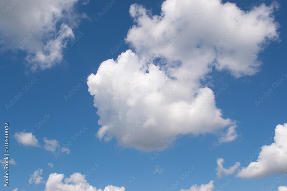 Beautiful white cumulus clouds slowly floating against a clear blue sky