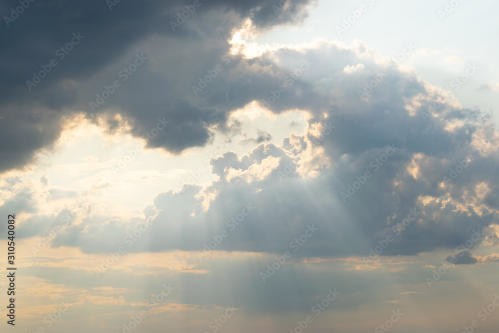 Obraz premium The sun's rays break through rare gaps among the dark thunderclouds hiding the sky