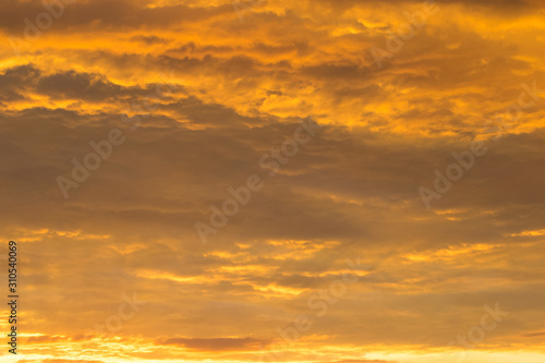 The dense relief layer of clouds is illuminated from below by the golden rays of the setting sun.