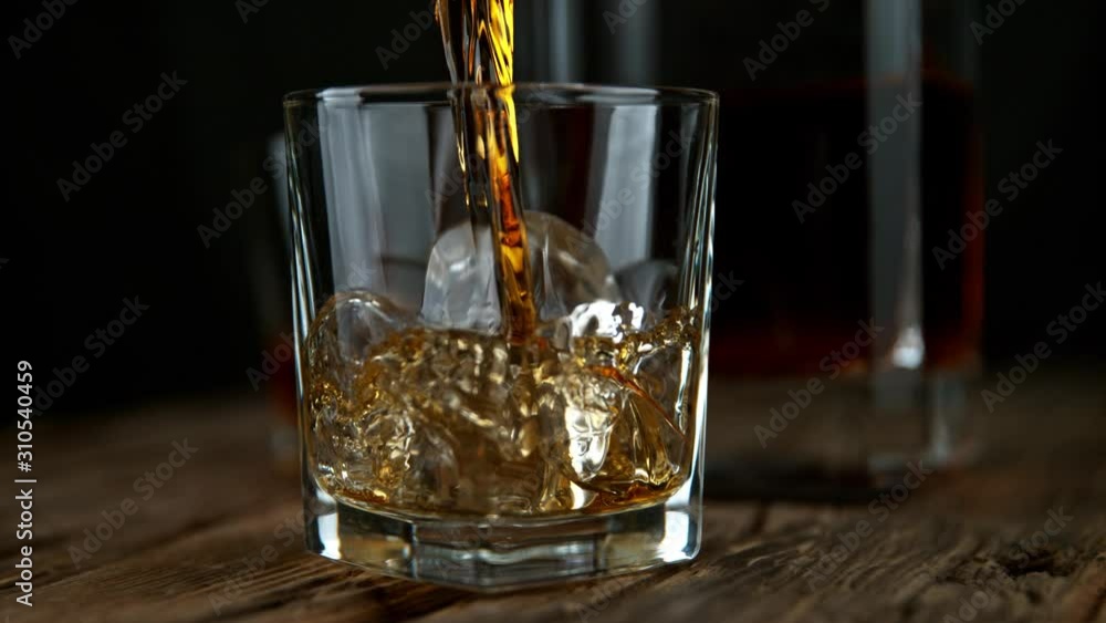 Super Slow Motion Shot of Pouring Whiskey into Glass with Ice Cubes at 1000fps with Camera Movement. Super Slow Motion Shot of Pouring Whiskey into Glass with Ice Cubes at 1000fps with Camera Movement.