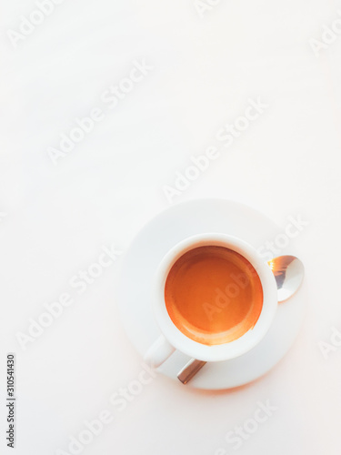 Full cup of coffee and spoon on white background. Top view.