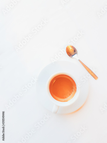 Full cup of coffee and spoon on white background. Top view.