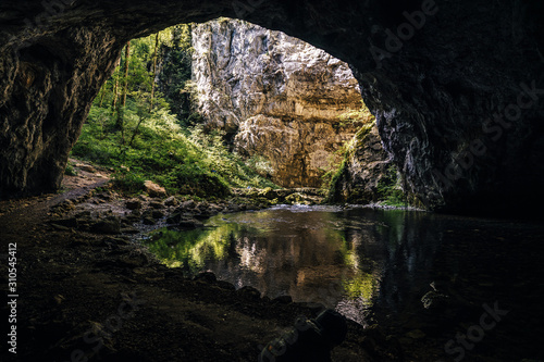 Famous old stone bridge in the karst caves of Rakov Skocjan area. Caves, underground river, depresions and skink holes of Natural park Rakov Skocjan Gorge, Slovenia. Small stone bridge over a stream.