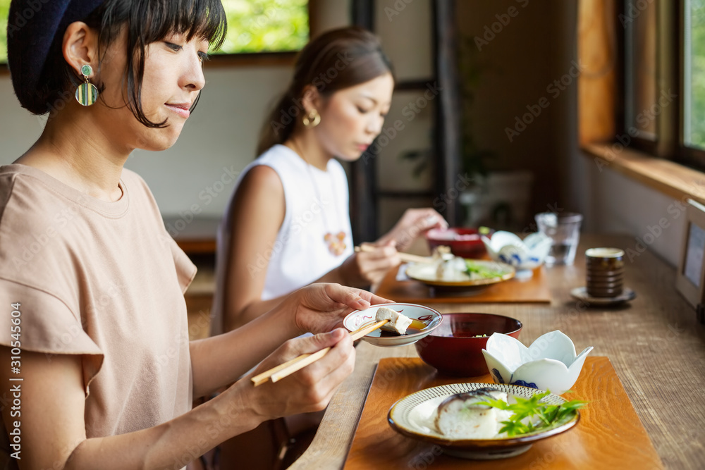 Two Japanese women sitting at a table in a Japanese restaurant, eating. Two Japanese women sitting at a table in a Japanese restaurant, eating.
