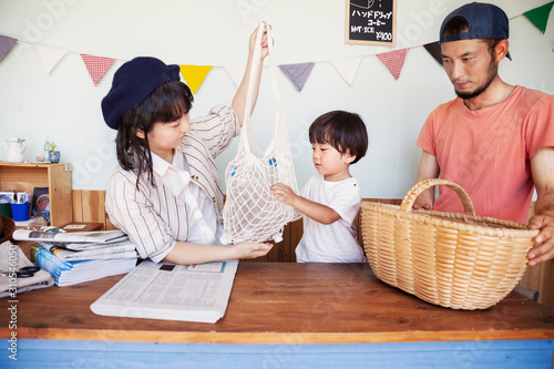 Japanese man, woman and boy standing in a farm shop, sorting clear plastic bottles into basket. photo