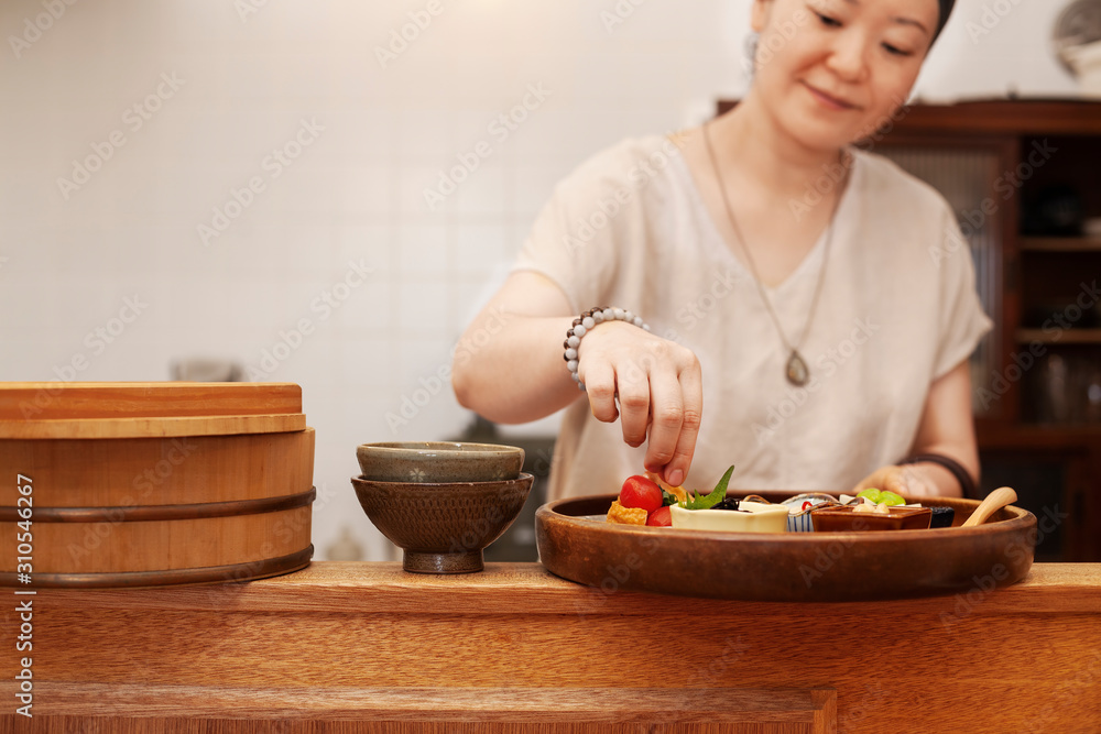 Japanese woman preparing fresh vegetables in a vegetarian cafe. Japanese woman preparing fresh vegetables in a vegetarian cafe.