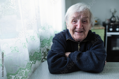 Elderly woman portrait near window in the house.