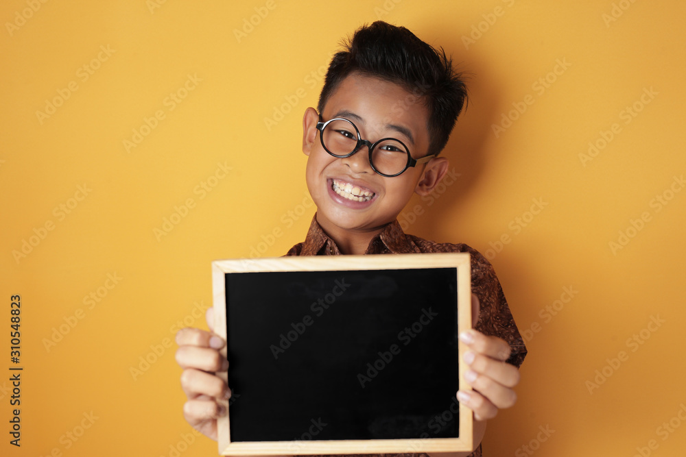 Smart Asian Boy Smiling at Camera and Showing Empty Blackboard Smart Asian Boy Smiling at Camera and Showing Empty Blackboard