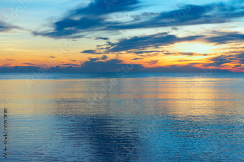 Smooth water surface in the sea and colorful sky in the morning.