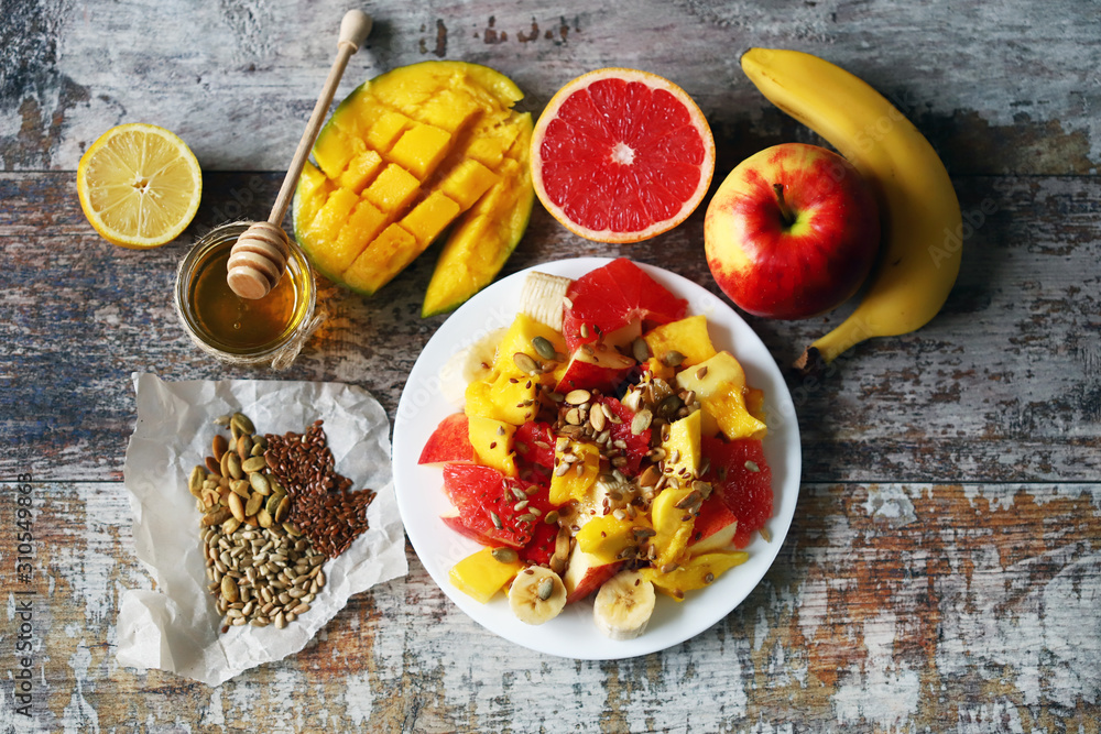 Selective focus. Fresh juicy fruit salad on a plate with mango, grapefruit and seeds. Healthy food. Vegan diet. Selective focus. Fresh juicy fruit salad on a plate with mango, grapefruit and seeds. Healthy food. Vegan diet.