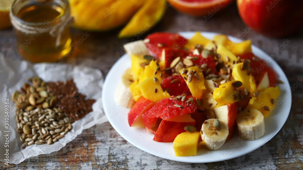 Selective focus. Fresh juicy fruit salad on a plate with mango, grapefruit and seeds. Healthy food. Vegan diet. Selective focus. Fresh juicy fruit salad on a plate with mango, grapefruit and seeds. Healthy food. Vegan diet.