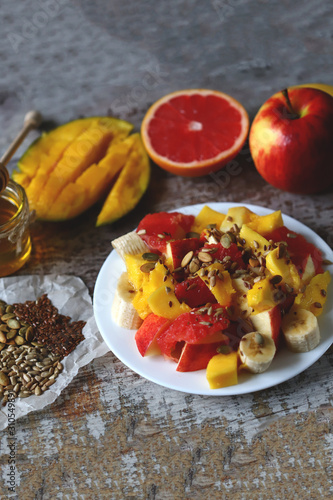 Selective focus. Fresh juicy fruit salad on a plate with mango, grapefruit and seeds. Healthy food. Vegan diet.