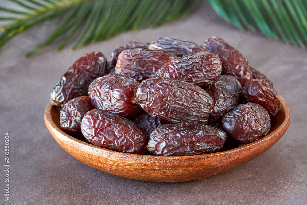 Dried dates fruit in wooden bowl . Close up 