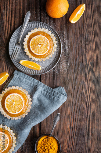 Whole-wheat turmeric tartlets filled with apricot jam, decorated with dried oranges, topped with powdered sugar photo