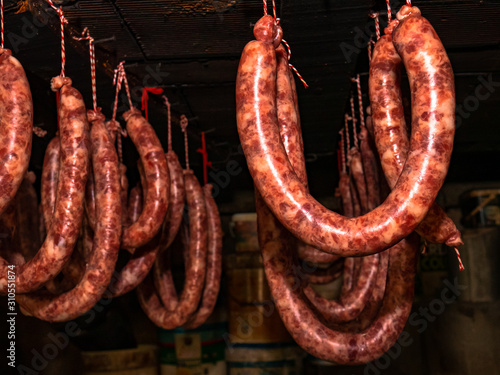 Sausages, loins and ribs hanging from the ceiling of a room to proceed to the smoked sausage