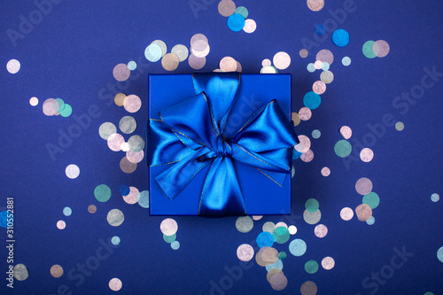 Blue present box with bow in monochrome trendy flat lay composition with confetti