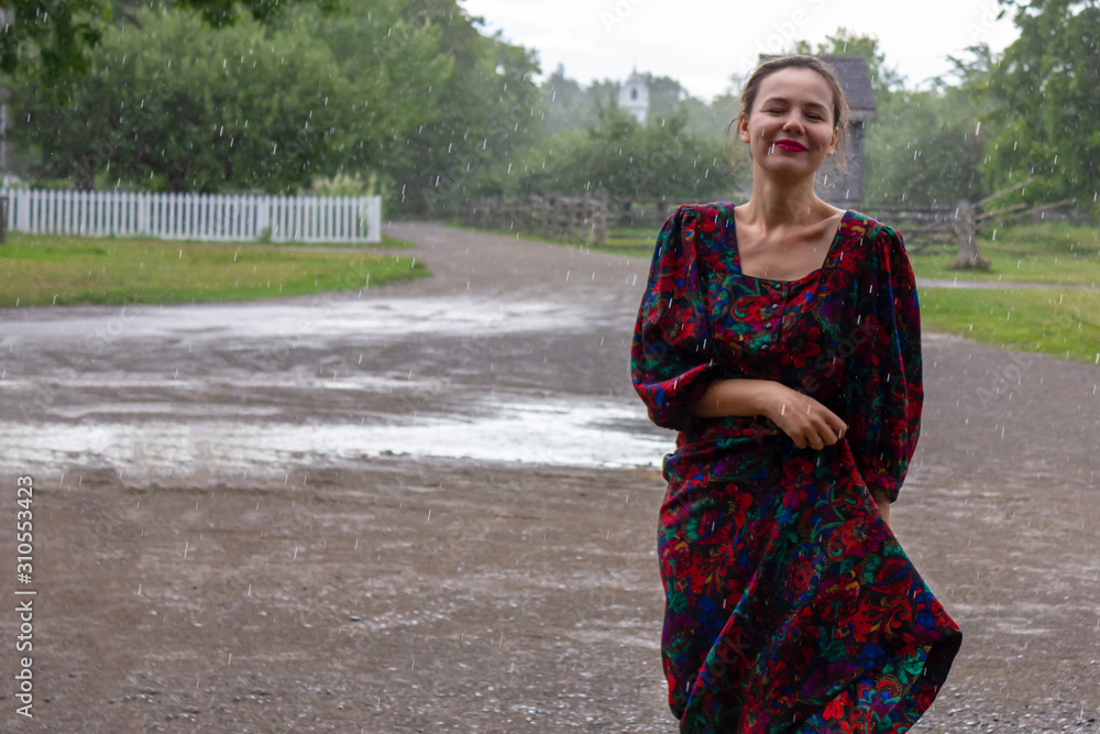 Fototapeta premium happy young Ukrainian woman is dancing under the rain in a rural farm area in summer