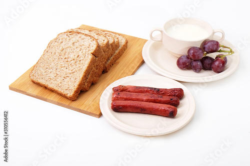 Whole grain bread, sausages and grapes serve with milk..