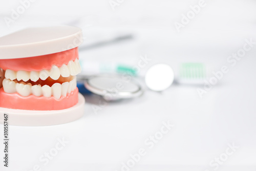 Dental care concept - dentist tools with dentures dentistry instruments and dental hygiene and equipment checkup with teeth model and mouth mirror oral health