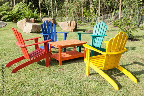 Fotomurale set of wooden chairs painted with vibrant colors; Photo in natural environment
