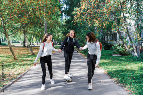 3 girls girlfriends teenagers, ride skateboard, day city street, happy smile, rejoice have fun after school college. Emotions relaxation entertainment, walk casual wear. Sneakers jeans sweater.