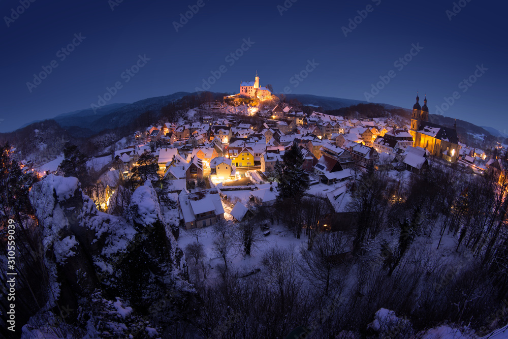 Gößweinstein, Germany, night view on quaint small town in Bavaria in winter. Castle in the center of the image, a basilica to the right.