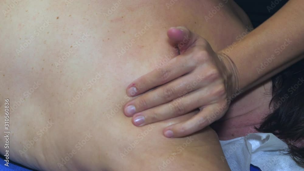 A naked back of the lady being massage by the therapist