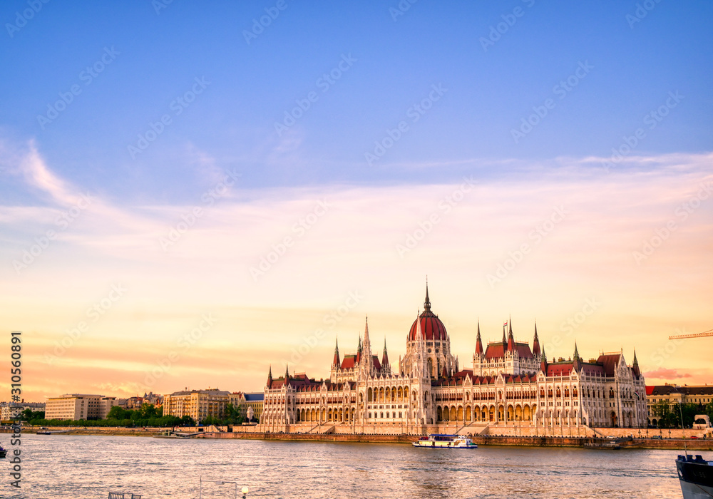 Obraz premium Budynek parlamentu węgierskiego położony nad Dunajem w Budapeszcie na Węgrzech o zachodzie słońca.