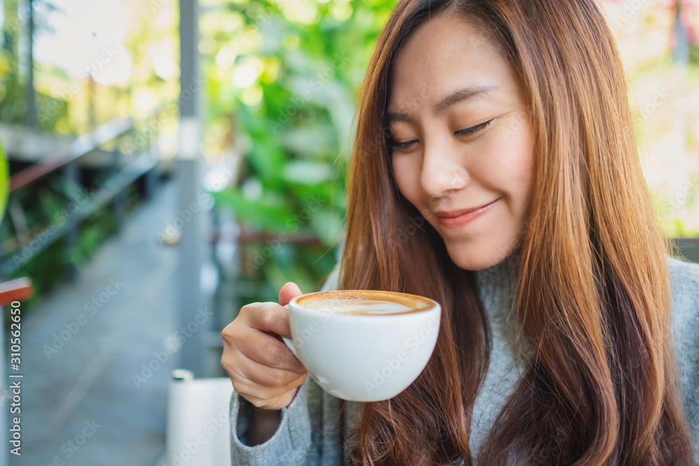 Closeup image of a beautiful asian woman holding a cup of hot coffee to drink Closeup image of a beautiful asian woman holding a cup of hot coffee to drink