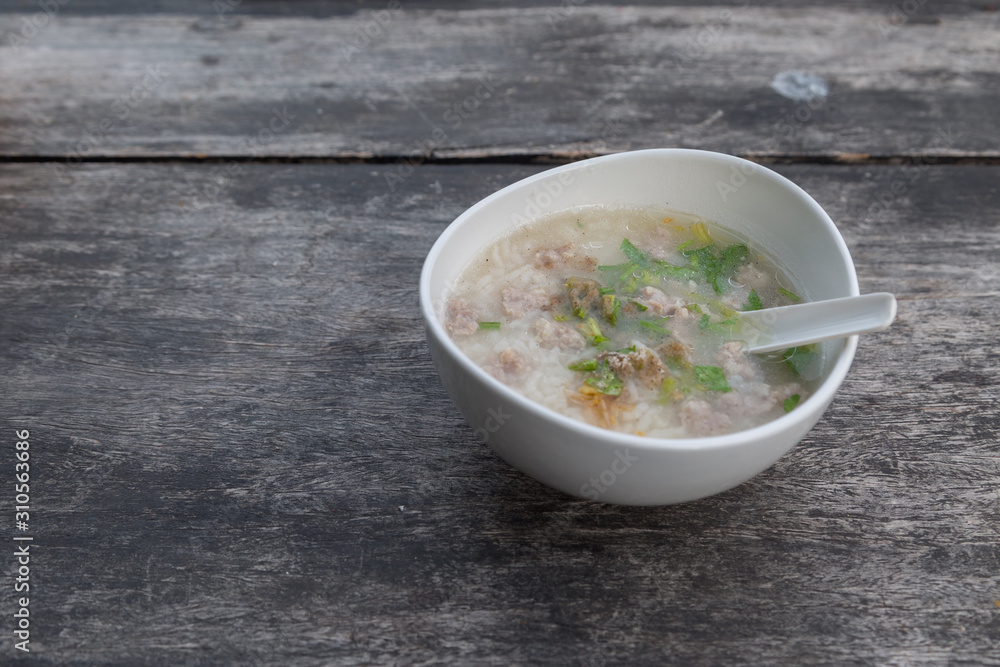 Pork porridge in a white cup on wooden table Pork porridge in a white cup on wooden table