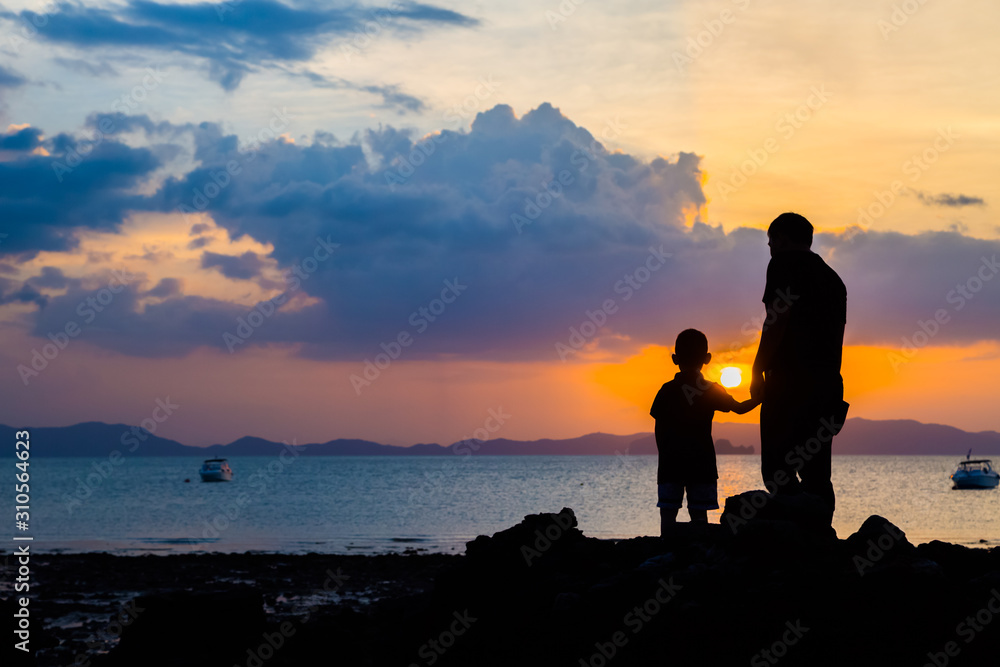 Silhouette image of father and son at the beach