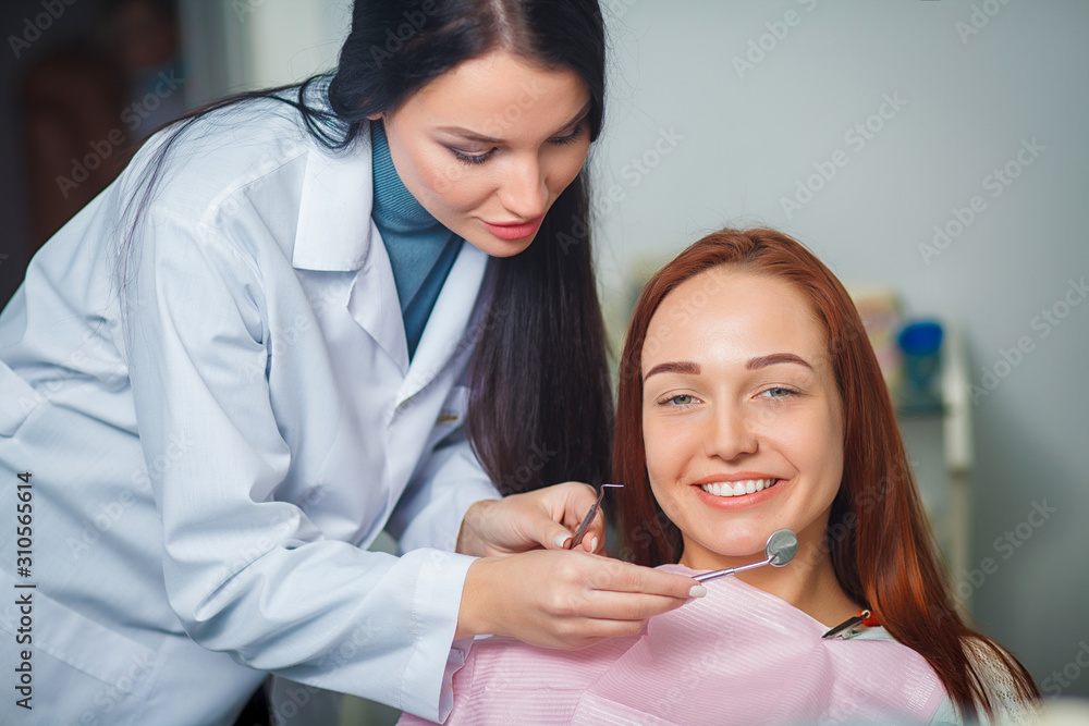 Young beautiful woman with beautiful white teeth sitting on a dental chair. Portrait of a woman with toothy smile sitting during examination at the dental office