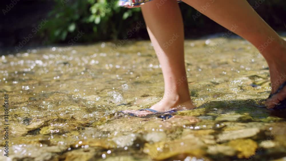 Woman walks down river wearing blue flip flops in slow motion 8K Woman walks down river wearing blue flip flops in slow motion 8K