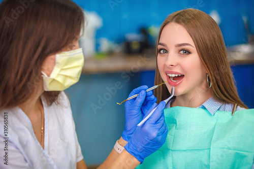 Young beautiful woman with beautiful white teeth sitting on a dental chair. Portrait of a woman with toothy smile sitting during examination at the dental office