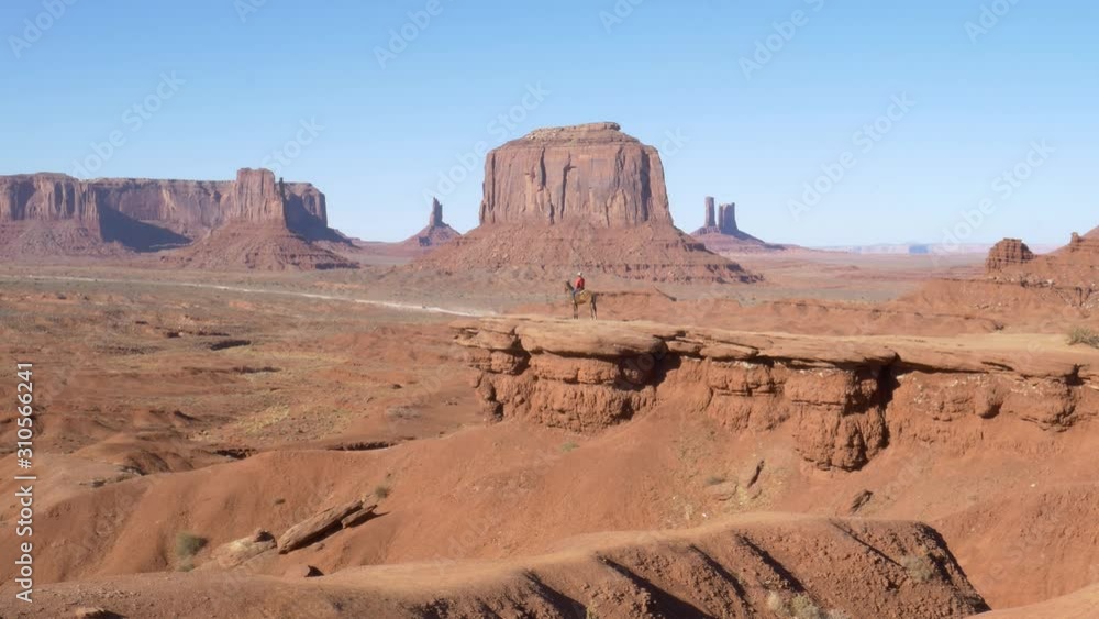 Monument Valley, Arizona, United States Of America - Man Riding A Horse On A Sunny With Scenic Rock Formation In The Background - Wide Shot Monument Valley, Arizona, United States Of America - Man Riding A Horse On A Sunny With Scenic Rock Formation In The Background - Wide Shot