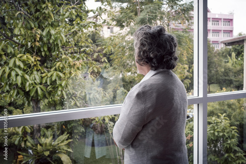 back view, Portrait of elderly Asian senior woman with grey hair looking out window for thinking seriously, lifestyle concept