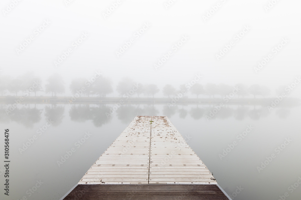 Floating fishing pier in the fog with treeline in background
