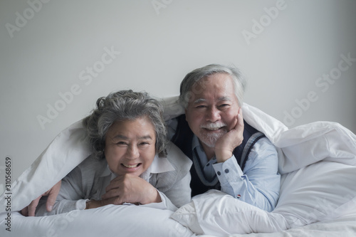 elderly couple caucasian senior man and woman sleep on bed and smiling in white blanket in bedroom, retirement health care with love lifestyle concept