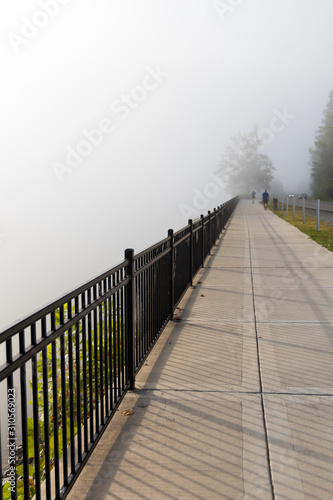 Fototapeta Naklejka Na Ścianę i Meble -  Sidewalk with joggers in the fog
