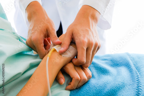 Slika na platnu Close up male doctor holding Asian female patient hand at hospital bed and hand